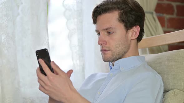 Portrait of Young Man Scrolling on Smartphone