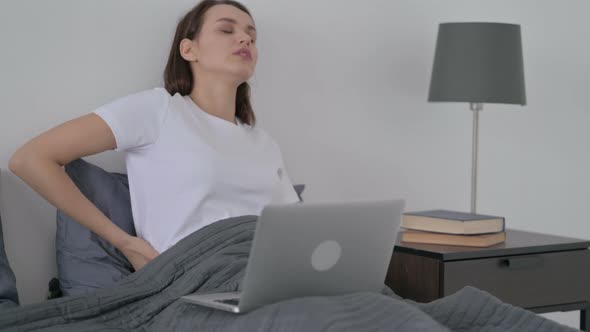 Woman with Back Pain Working on Laptop in Bed