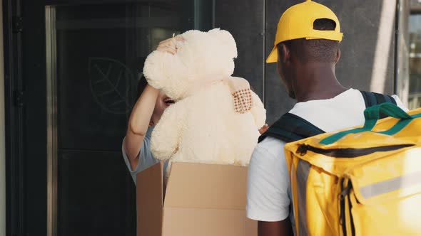 Courier Bring a Parcel to a Little Girl with Mom at the Door of the House