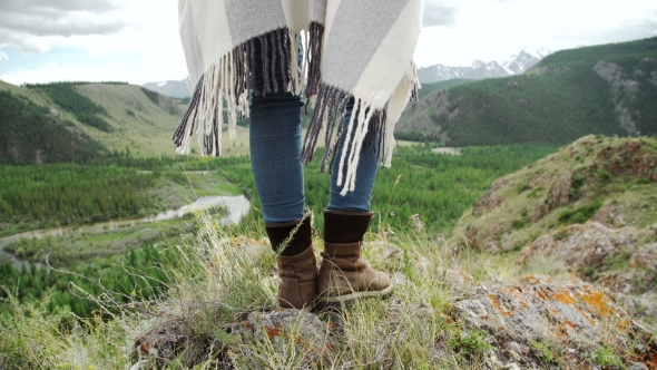 Young Beautiful Woman Traveler Wearing Hat And Poncho Relaxing On The Top Of The Hill With Mountains