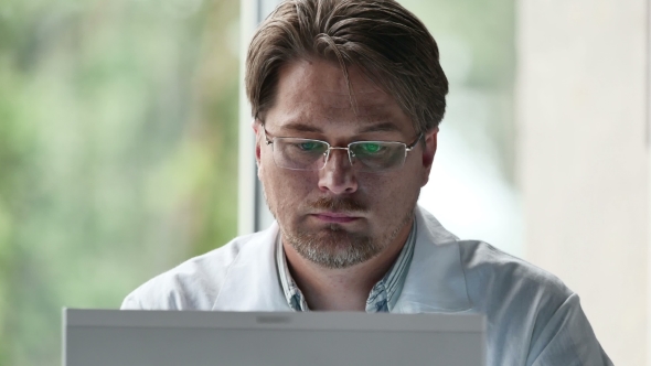 Portrait Of Serious Male Doctor Using Computer In Clinic