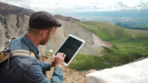 Man's Hands Touching Screen Of Digital Tablet On The Background Of Mountains
