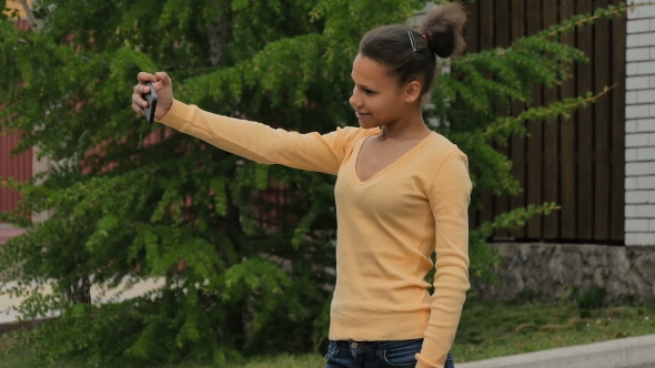 Young Biracial Girl Makes Selfie Phone Standing On The Street