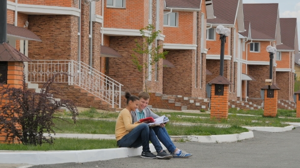 Couple Teenagers Sitting And Look Books