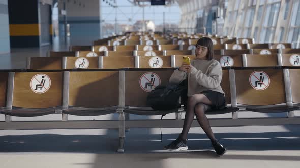 Full Length View of the Young Caucasian Tourist Woman Sitting Alone with Distance at the Airport and