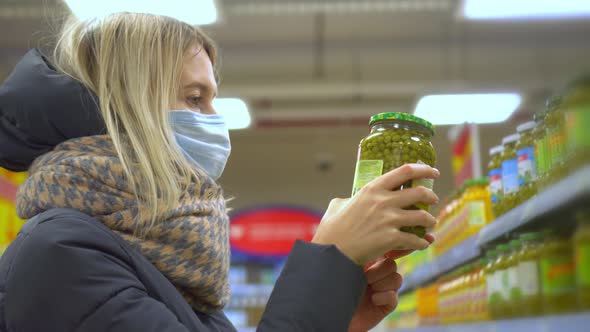 A woman chooses canned peas in a supermarket. Shopping in the store.