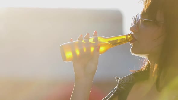 Young Woman Drinking Beer From Bottle Outdoors