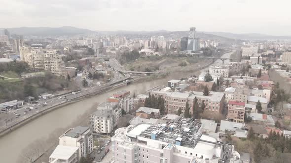 Flying over Kura river in Tbilisi. Beautiful aerial view of King Tamar bridge