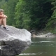Young Beautiful Girl Sitting On The Big Stone Near Mountain River - VideoHive Item for Sale