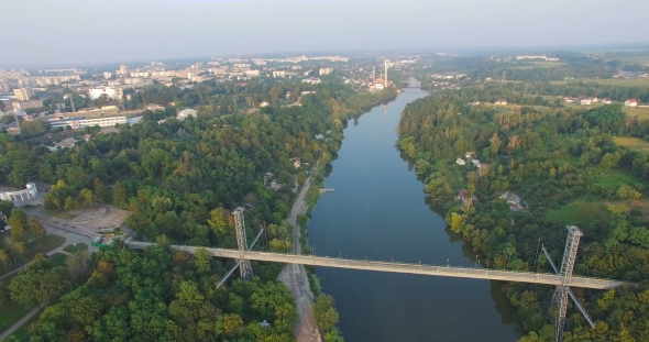 Suspension Footbridge Over The River Between The Town And Forest