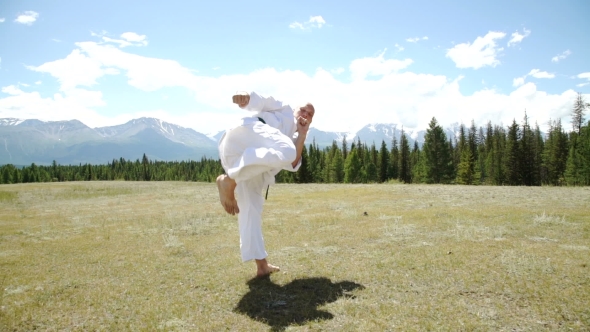 Fighter Performing Karate Stance Against Rock Crashing Down From Cliff