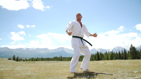 Fighter Performing Karate Stance Against Rock Crashing Down From Cliff