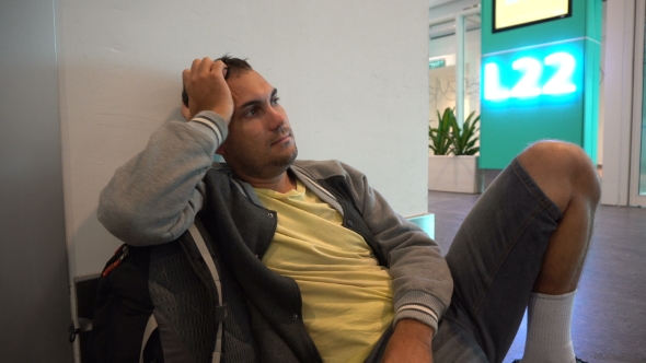 Tired Male Traveler Sitting At The Airport