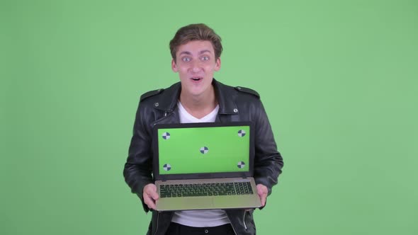 Happy Young Rebellious Man Showing Laptop and Looking Surprised