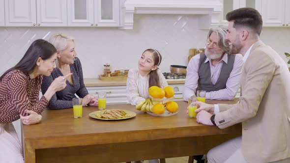 Happy Family Clinking Glasses with Orange Juice While Celebrating Together Birthday of Little Girl