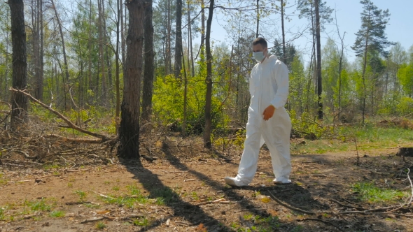 A Guy In a Special Suit Removes Trash In Forest