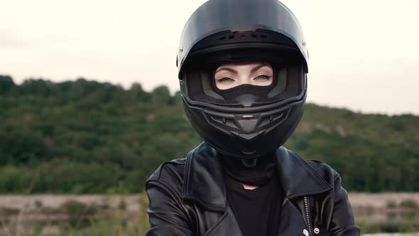 Young Stylish Motorcyclist Woman in Motorcycle Helmet and Leather Jacket