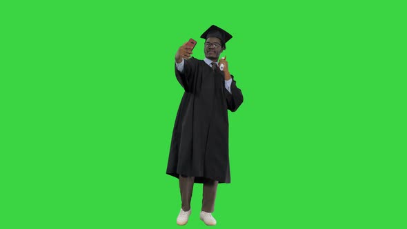 Happy African American Male Student in Graduation Robe Taking Phone Selfies with His Diploma on a