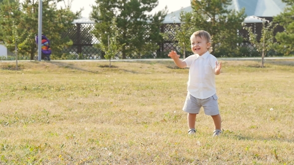 Young Happy Little Boy Smiling Greeting Someone In The Park