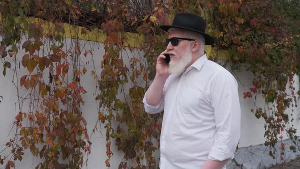 Old Man with Albinism Talking on the Phone While Walking Next To His House