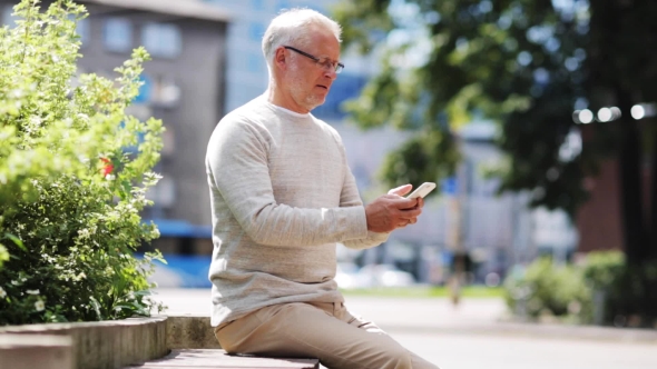 Senior Man Texting Message On Smartphone In City