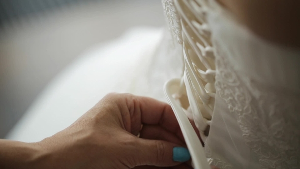 Mother Helps Her Daughter To Fasten Foundation Garment On Her Wedding Dress.