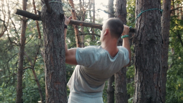 Man Reaching for a Branch Lashed to a Tree Back View
