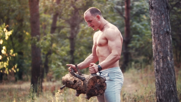 Muscular Topless Sportsman Doing Biceps Curls in Forest