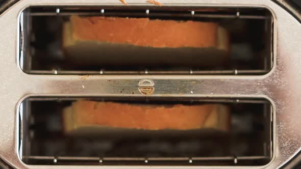 Sliced white bread going inside a toaster on kitchen table breakfast. Preparation of morning meal