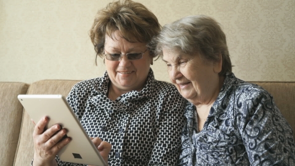 Two Women Watching Photos On a Digital Tablet