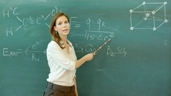 Smiley Teacher Standing At The Blackboard Where The Chemical Formula Is Written alt