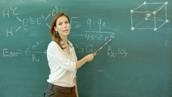Smiley Teacher Standing At The Blackboard Where The Chemical Formula Is Written