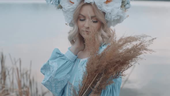 Woman in Ukrainian national costume with a wreath on her head. Embroidery. View of the river. Woman