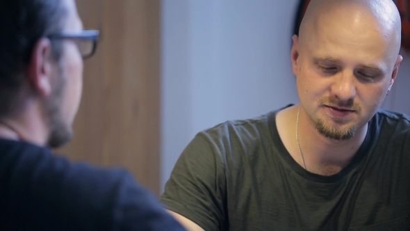 Two Men Speak With Each Other Sitting In Art Studio.