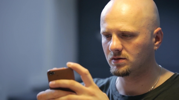 Bald Bearded Man Chats In Smartphone Sitting In Art Studio.