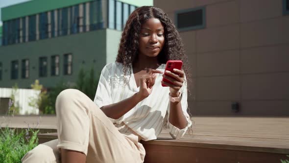 Young African Black Happy Woman Holding Smartphone Using Mobile Apps Outdoor