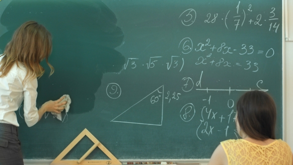 Female Teacher At High School Washes The Chalkboard And Lookng To The People In Class alt