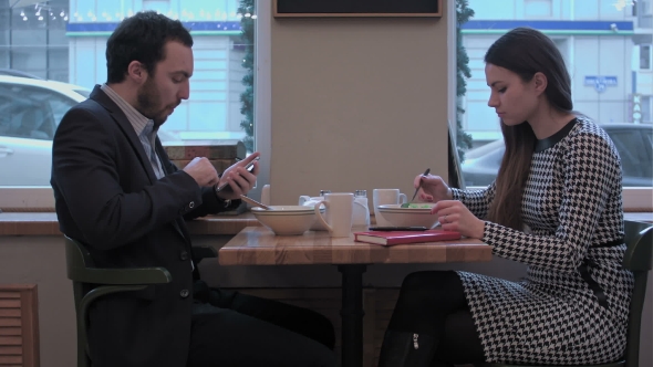 Business Partners Have Lunch At Cafe Use Smartphones