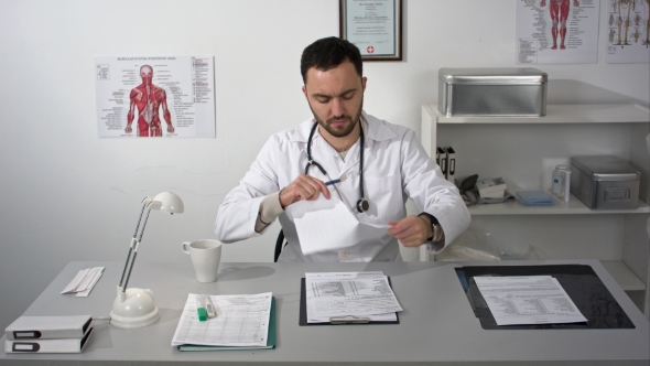 Young Serious Doctor Destroys Documents Sitting In Medical Office With Folder