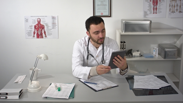 Male Doctor Having Video Conference Useing Tablet Gadget