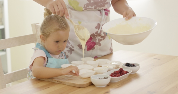 Parent Pouring Muffin Batter Into Holders