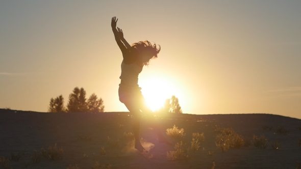 Silhouette Of a Girl a Professional Dancer Jumping At Sunset In The Desert