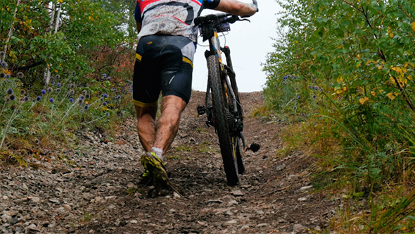 Male Athlete a Cyclist Climbs Uphill