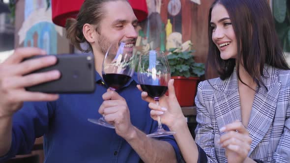 Happy Couple With Wine Taking Photos On Phone At Restaurant