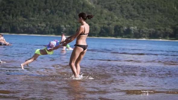 Mother Playing Turning Around Her Baby Girl Daughter In The Lake