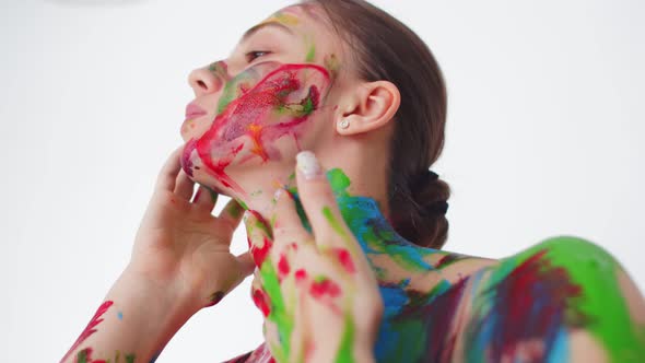 Female hands stained in colored paint are held on the neck of a dancing woman, close-up. Young woman