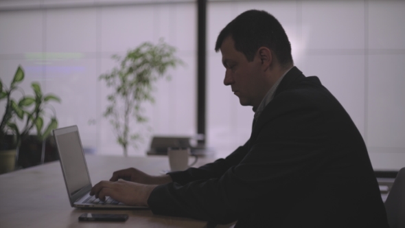 Middle-aged Man In The Office At The Table, Working On The Computer.