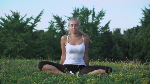 Young Beautiful Girl Sits On a Hill, Meditating And Enjoying The Sun.