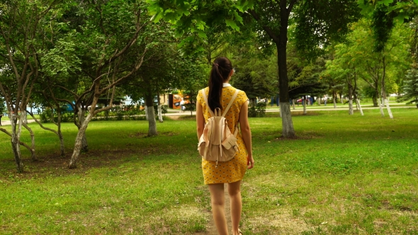 Footage Woman Walking In The Park With a Backpack. 