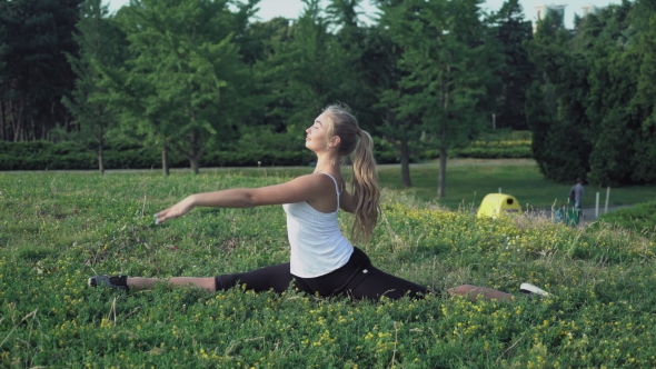 Blonde Girl Sits On a Hill And Doing The Exercises Right And Left Turns.